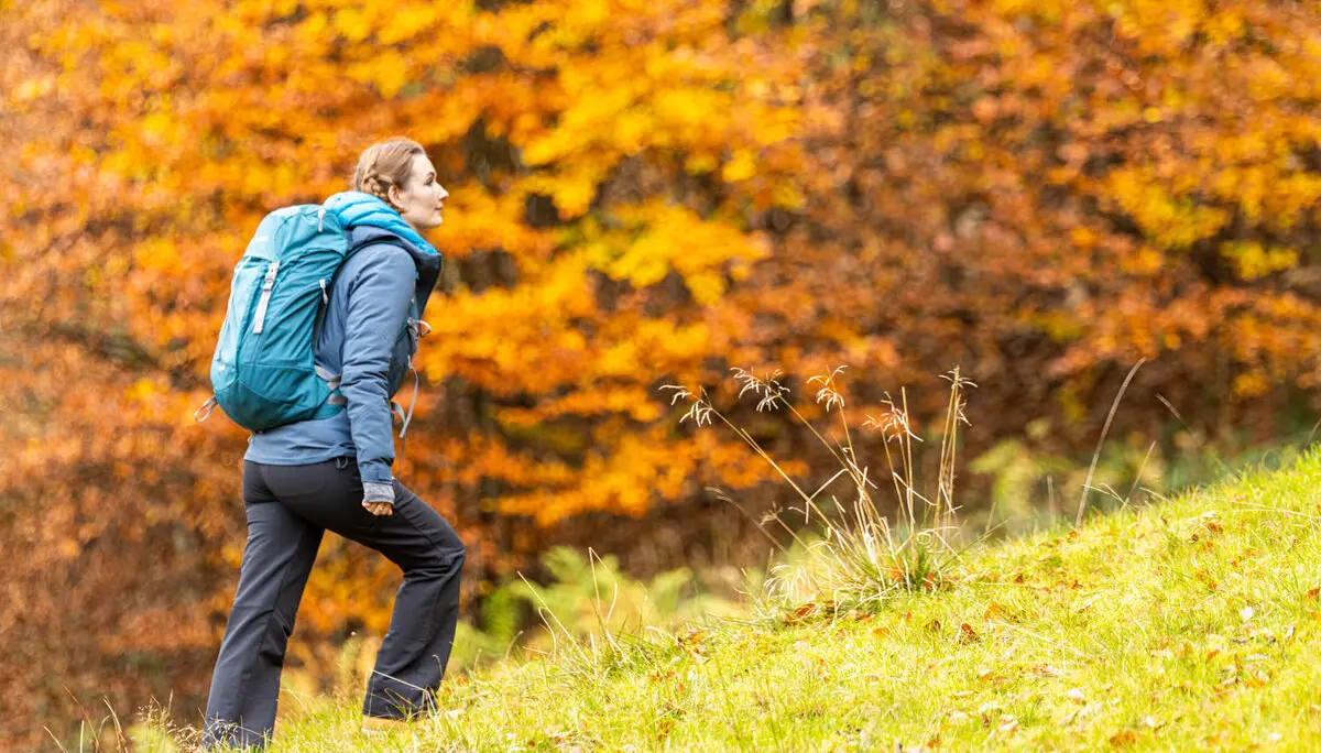 Wandern im Herbst: Eine Frau genießt die herbstliche Stimmung in den Bergen. Das Laub ist bereits bunt verfärbt | © DAV / Franz Günther