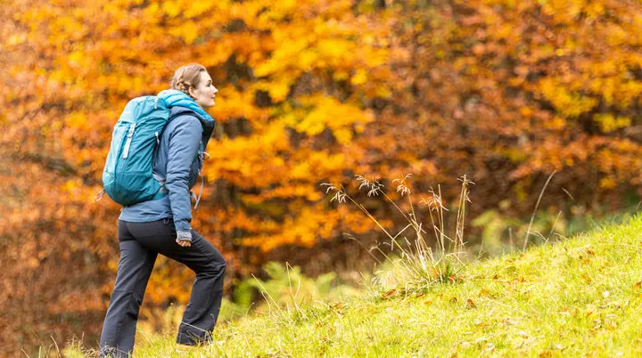 Wandern im Herbst: Eine Frau genießt die herbstliche Stimmung in den Bergen. Das Laub ist bereits bunt verfärbt | © DAV / Franz Günther